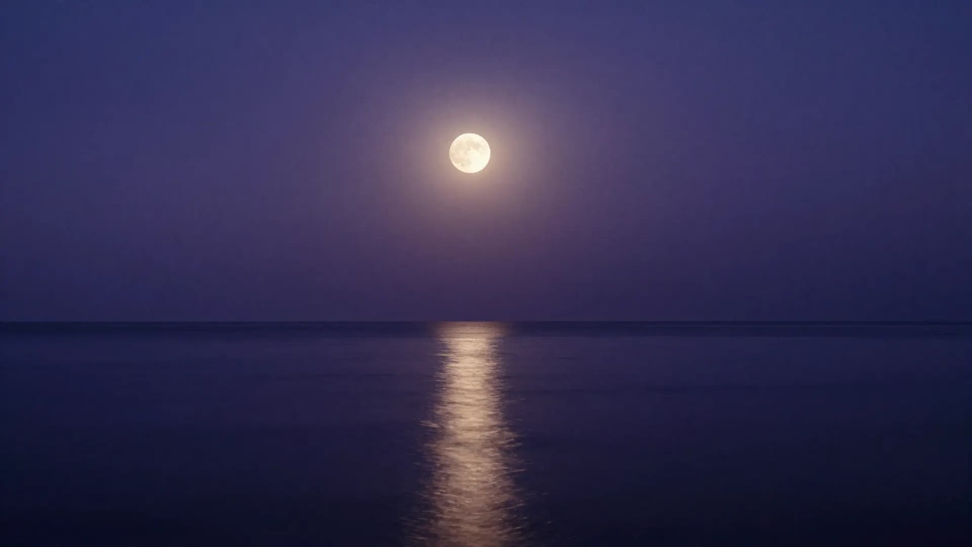 A full moon low over a dark sea, drawing a path of light on the water